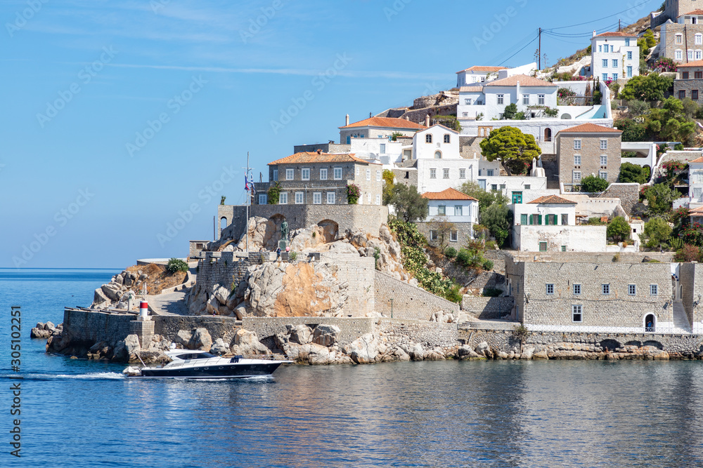 Houses and buildings in the mountains with trees and vegetation and boat in Hydra Island