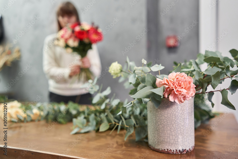 European floral shop concept. Florist woman creates red beautiful bouquet of mixed flowers. Handsome fresh bunch. Education, master class and floristry courses. Flowers delivery. European floral shop concept. Florist woman creates red beautiful bouquet of mixed flowers. Handsome fresh bunch. Education, master class and floristry courses. Flowers delivery.