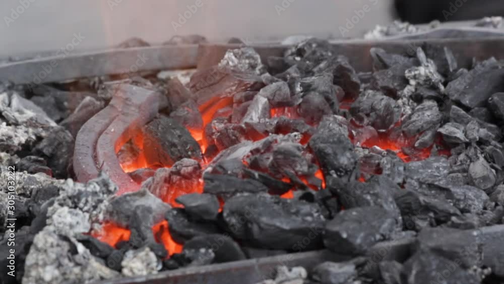 Annealing and heat-treating of iron horseshoe for forging. Embers glow in a iron forge. Static camera. Annealing and heat-treating of iron horseshoe for forging. Embers glow in a iron forge. Static camera.