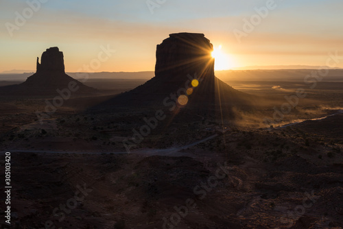 Sunrise flares behind the buttes in Monument Valley, Navajo Nation, Arizona