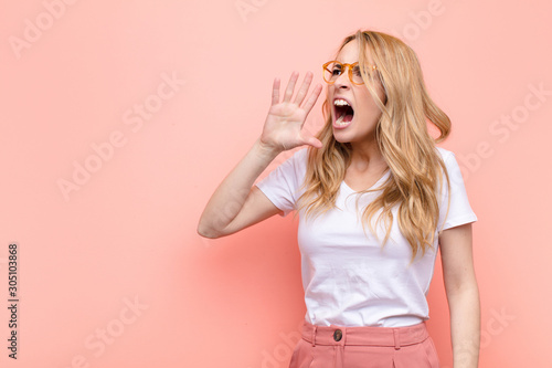 Tableau sur toile young pretty blonde woman yelling loudly and angrily to copy space on the side,