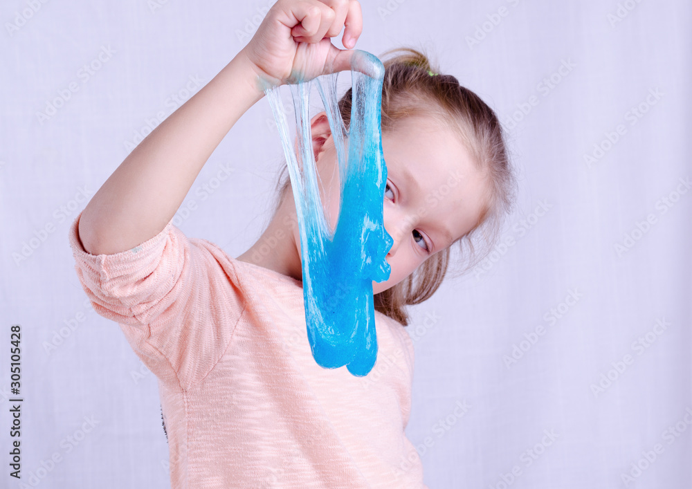 Adorable little girl holding slime toy, worldwide popular self made toy. Kid playing with slime squeeze and stretching it. Stock Photo | Adobe Stock Adorable little girl holding slime toy, worldwide popular self made toy. Kid playing with slime squeeze and stretching it. Stock Photo | Adobe Stock