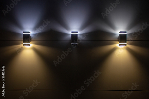 three lamps on the wall shining at night.