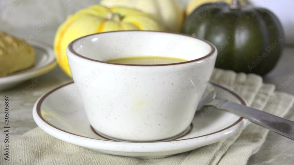 Serving a cup of homemade butternut squash soup with a ladle Serving a cup of homemade butternut squash soup with a ladle