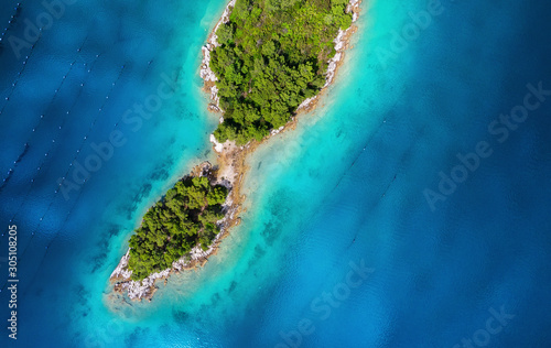 Islands with trees in the middle of the sea. Turquoise water in the Mediterranean Sea. Summer landscape in Croatia from the air.