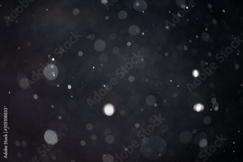 Abstract falling snow or rain bokeh texture overlay on blue background. © Andrii Arkhipov