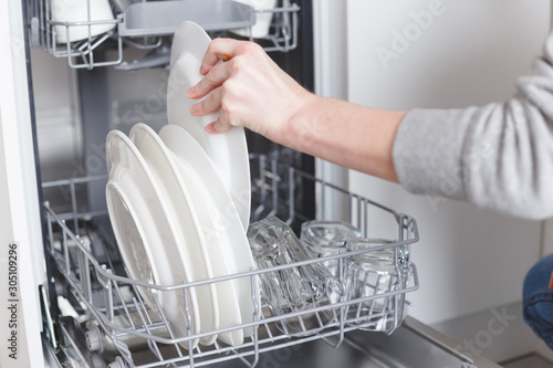 Housework: young woman putting dishes in the dishwasher photo