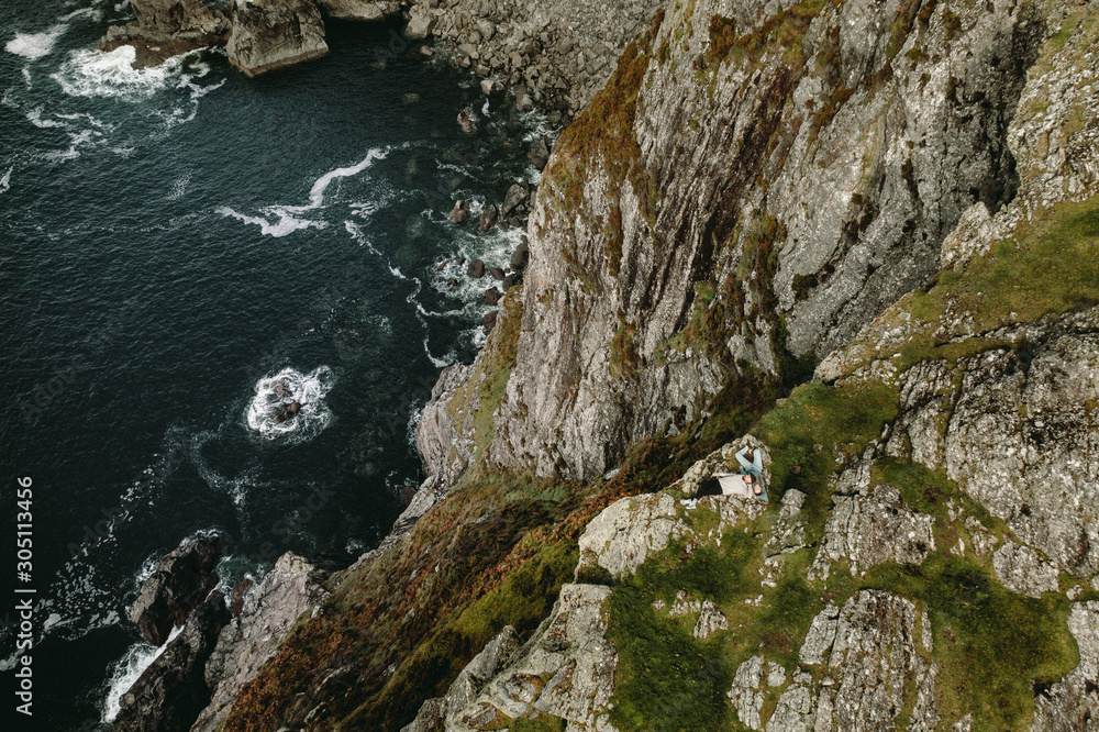  aerial shot, a couple lies on a rocky shore of the Atlantic Ocean, the northern coast of Ireland