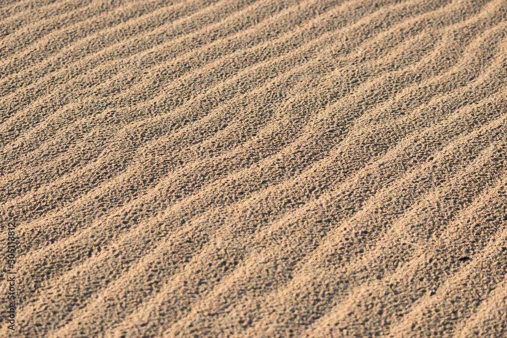 Close up beach sand texture with wavy ripple surface. Summer holiday travel concept.
