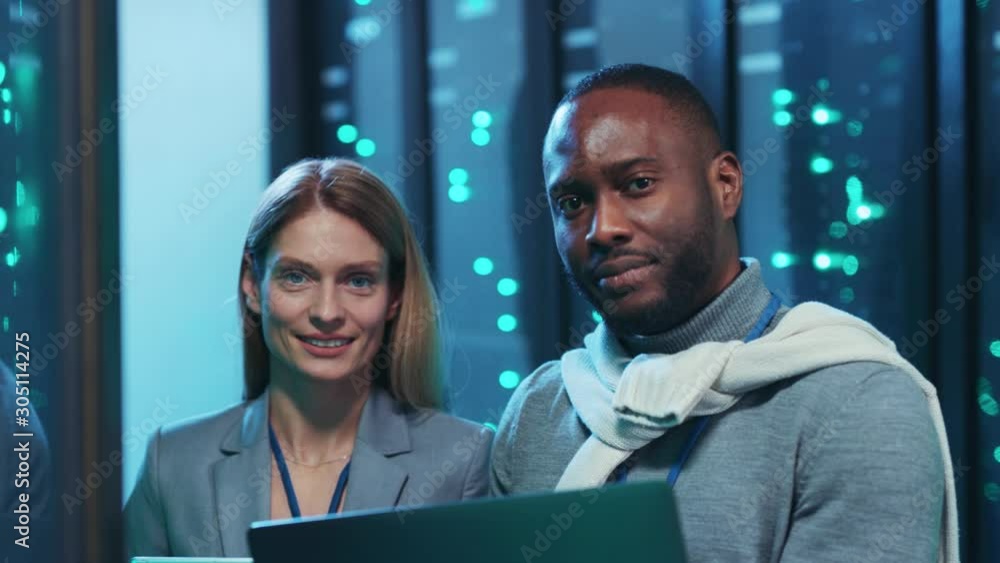Black server technician with head administrator using laptop inspecting digital server room cooperating in database center. Team portrait. People and technology. Black server technician with head administrator using laptop inspecting digital server room cooperating in database center. Team portrait. People and technology.
