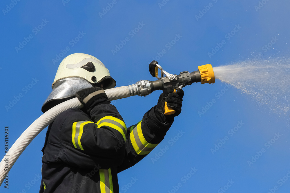 Firefighter spraying high pressure water to fire Firefighter spraying high pressure water to fire