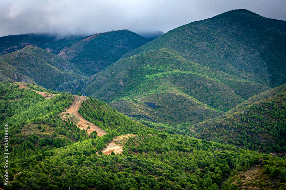Cortafuegos en una montaña de Sierra Lujar,con los picos de las montañas tapados por las nubes bajas.