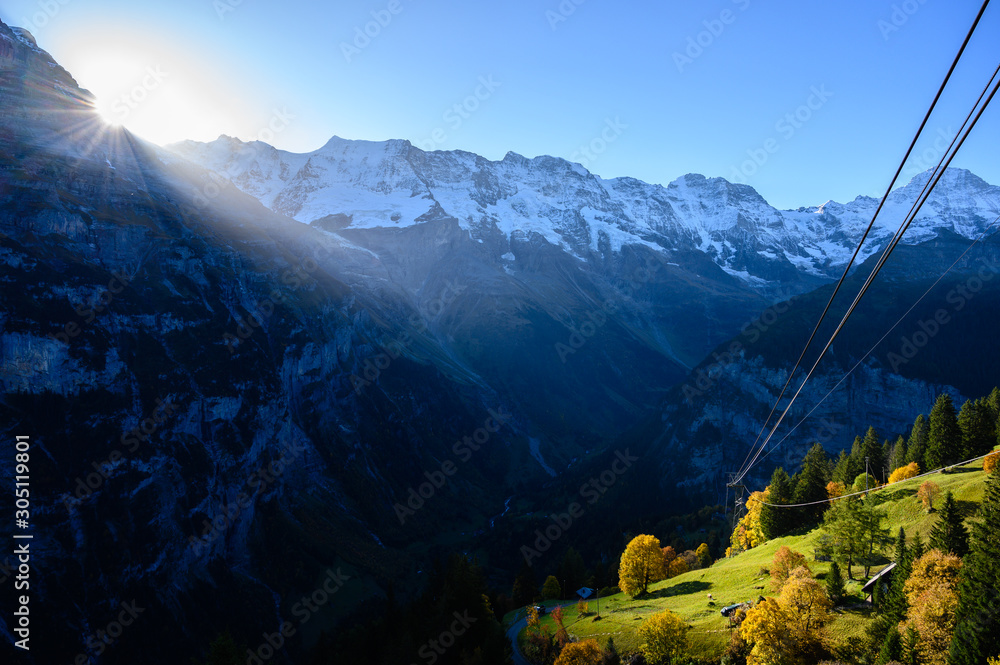 Sunrise over the mountains. Causing light to fall into the forest in autumn, Mürren Switzerland.