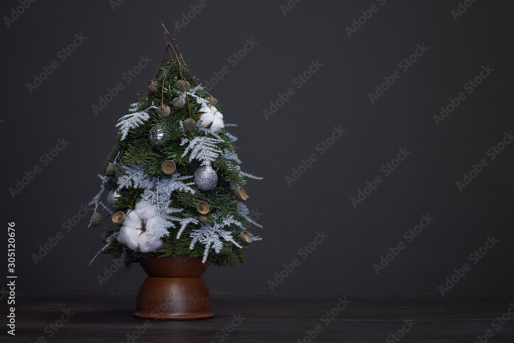 Christmas and New Year composition. Christmas tree made of fir branches and decorated by natural materials and balls in a clay pot