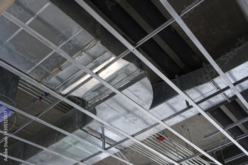 Install the air duct system above the ceiling structure inside the building.