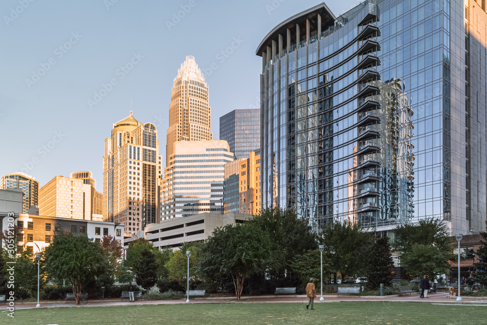 Person walking on a park with modern buildings in the background