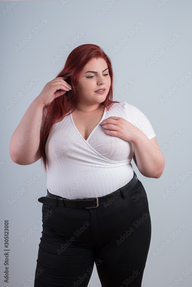 Young obese woman in casual clothes on a white background in the studio. Bodypositive and improper nutrition. Young obese woman in casual clothes on a white background in the studio. Bodypositive and improper nutrition.