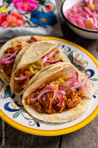 Mexican cochinita pibil tacos with habanero sauce on wooden background