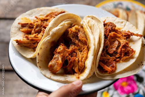 Mexican cochinita pibil tacos with habanero sauce on wooden background