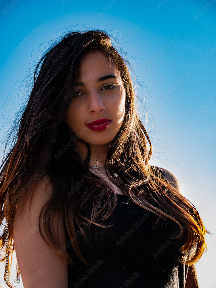 Fototapeta premium Close-up portrait of young long-haired brunette smiling at the beach