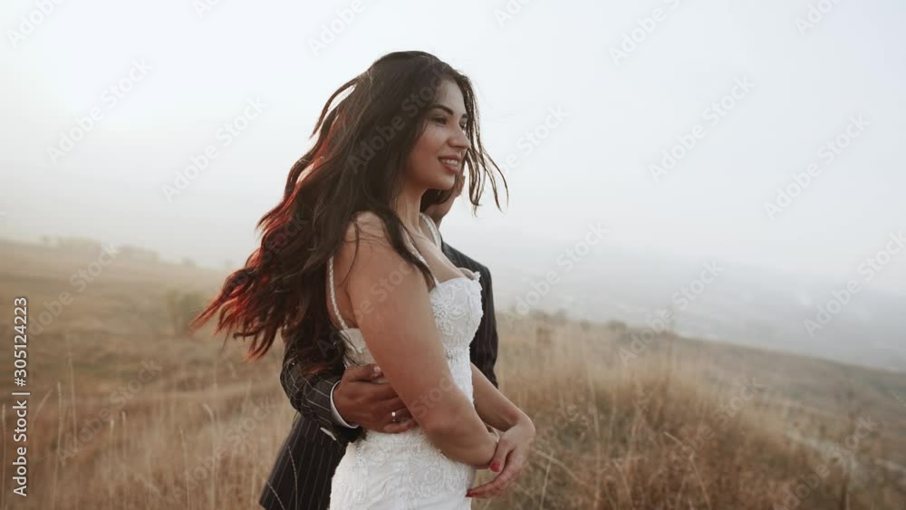 Groom holds bride in his arms on a mountain hills. Wedding couple. Happy family. Man and woman in love. Lovely groom and bride. Wedding day Groom holds bride in his arms on a mountain hills. Wedding couple. Happy family. Man and woman in love. Lovely groom and bride. Wedding day