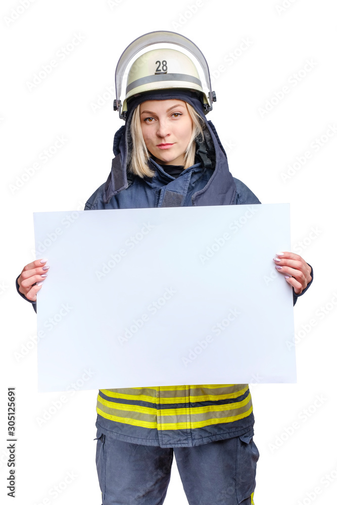 young beauty firefighter wearing uniform and helmet looking to the camera and holding empty paper sheet in hands. young beauty firefighter wearing uniform and helmet looking to the camera and holding empty paper sheet in hands.