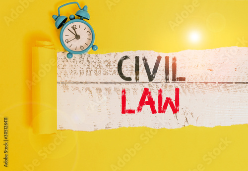 Conceptual hand writing showing Civil Law. Concept meaning Law concerned with private relations between members of community Alarm clock and torn cardboard on a wooden classic table backdrop photo