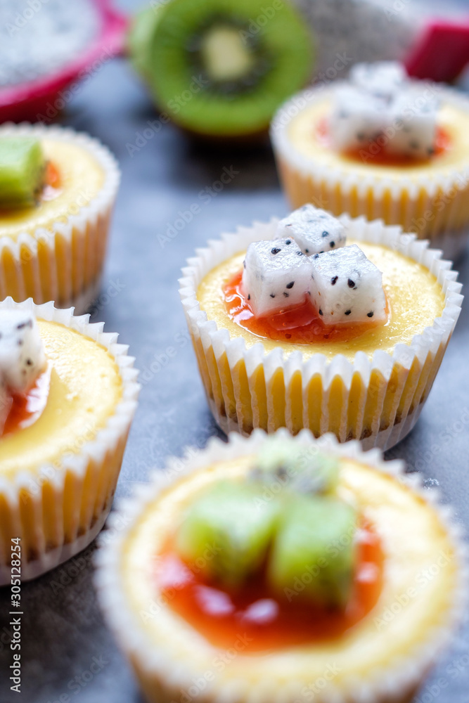 Mini New York Cheesecakes Recipe with Kiwi fruit and Dragon fruit on  wooden board.