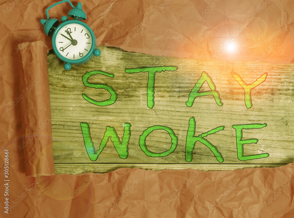 Writing note showing Stay Woke. Business concept for being aware of your surroundings and things going on Keep informed Alarm clock and torn cardboard on a wooden classic table backdrop Writing note showing Stay Woke. Business concept for being aware of your surroundings and things going on Keep informed Alarm clock and torn cardboard on a wooden classic table backdrop