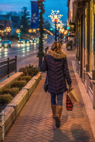 woman Christmas shopping in city carrying bags down street