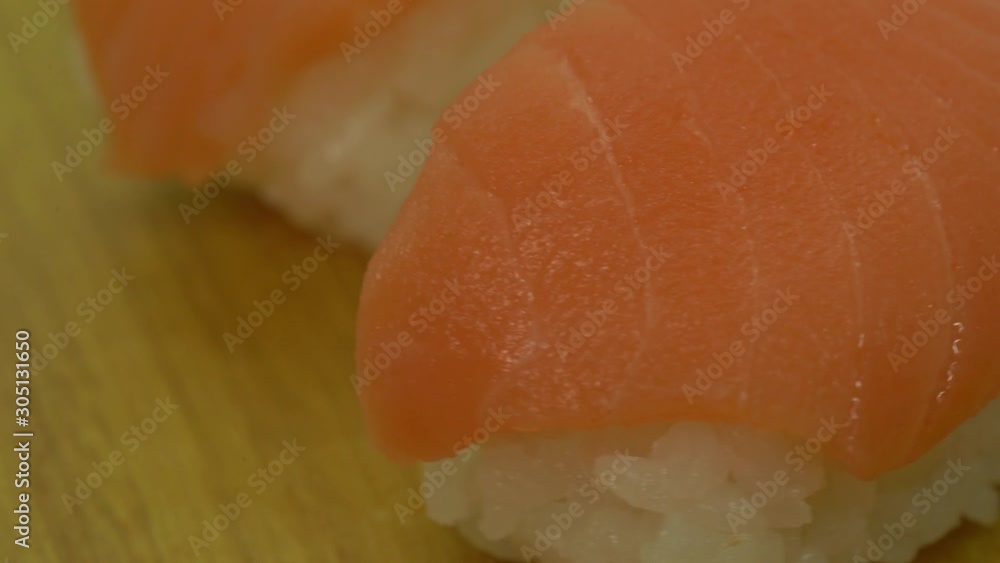 Cinematic closed-up rotating shot of fresh salmon sushi, Raw salmon served on a glutinous rice. A traditional japanese delicacies Cinematic closed-up rotating shot of fresh salmon sushi, Raw salmon served on a glutinous rice. A traditional japanese delicacies
