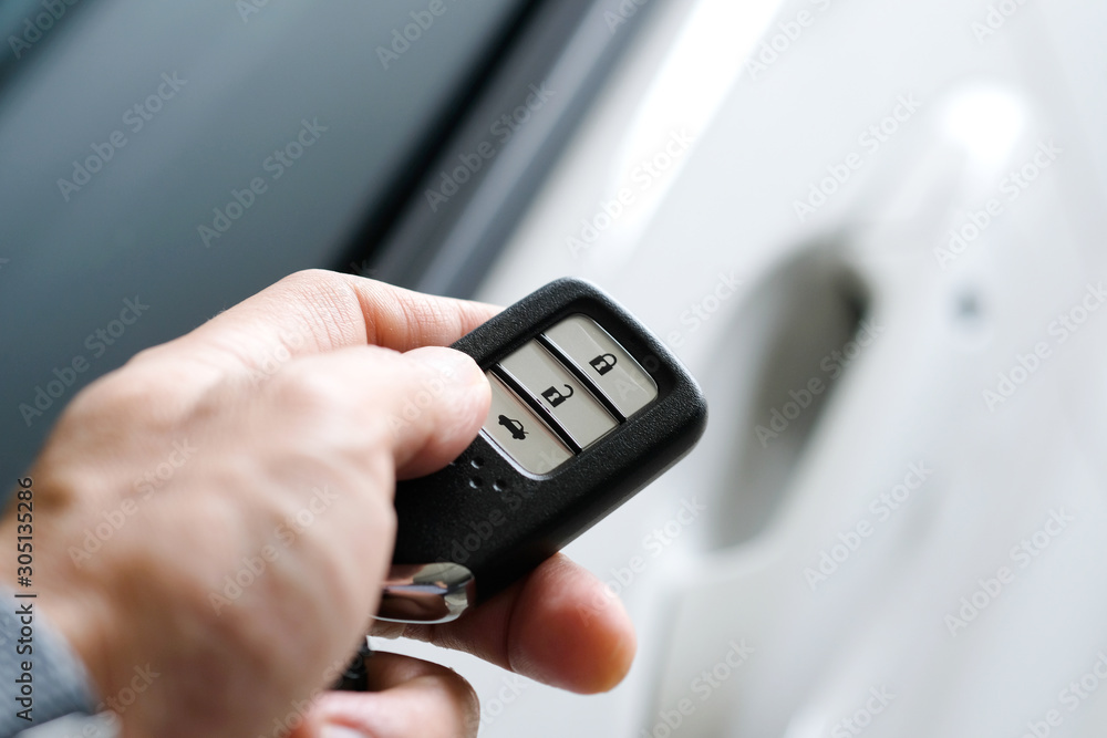 Man hand holding the car remote, he push the remote control to open the car door Man hand holding the car remote, he push the remote control to open the car door