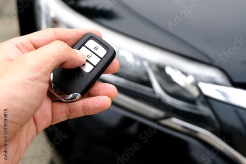 Man hand holding the car remote, he push the remote control to open the car door