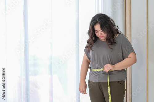 Asian fat women are sad because of the increase in size after checking with a tape measure.
