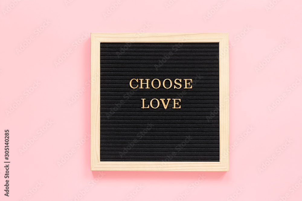 Fototapeta Choose love. Motivational quote in gold letters on black letter board on pink background, central composition . Top view Concept inspirational quote of the day. Template for Valentine card, postcard