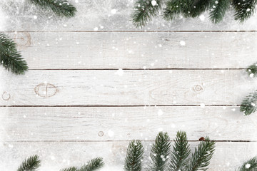 Pine leaves decorated as a frame on a white wooden background  with snowflakes. Merry Christmas and winter holiday background.