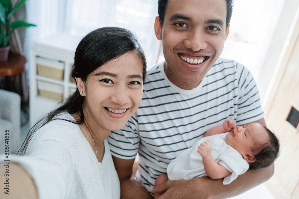 Selfie concept, cheerful family carrying little baby daughter at home Selfie concept, cheerful family carrying little baby daughter at home