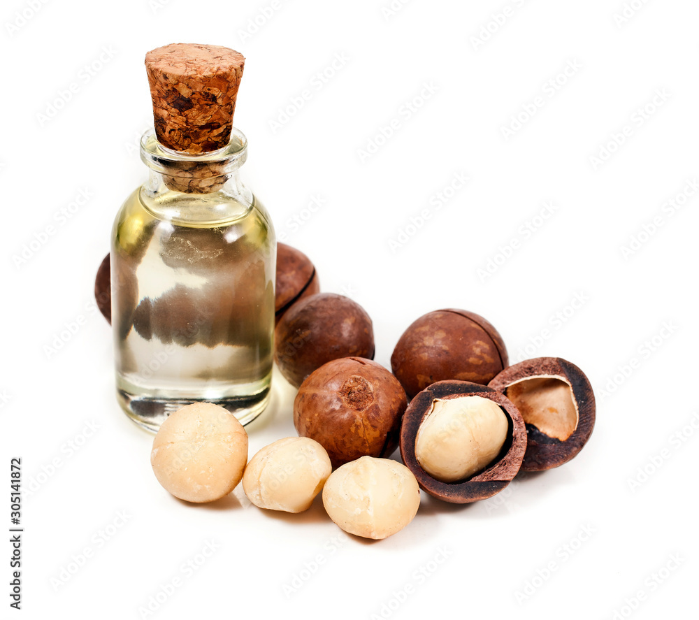 Macadamia nuts heap and macadamia oil in glass bottle isolated on a white background. Macadamia nuts heap and macadamia oil in glass bottle isolated on a white background.