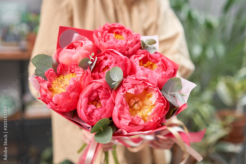 Mono bouquet of peonies, coral charm, in womans hands. Modern floral shop. Finished work of the florist. Delivery fresh cut flower from online store Mono bouquet of peonies, coral charm, in womans hands. Modern floral shop. Finished work of the florist. Delivery fresh cut flower from online store