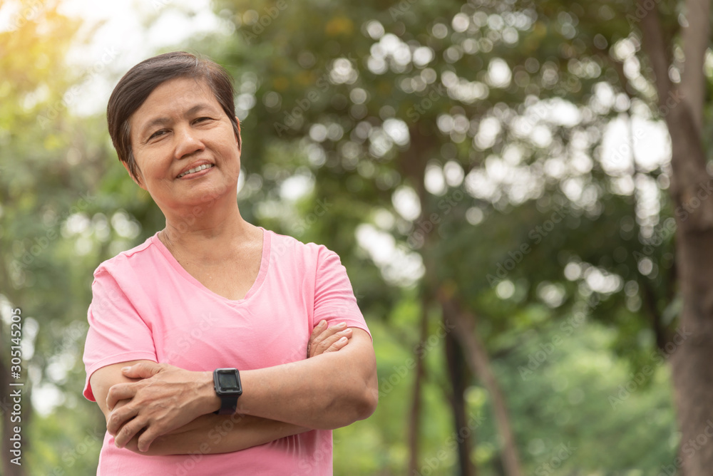 Asian Senior woman in pink shirt smiling with arms crossed before exercising. Asian Senior woman in pink shirt smiling with arms crossed before exercising.