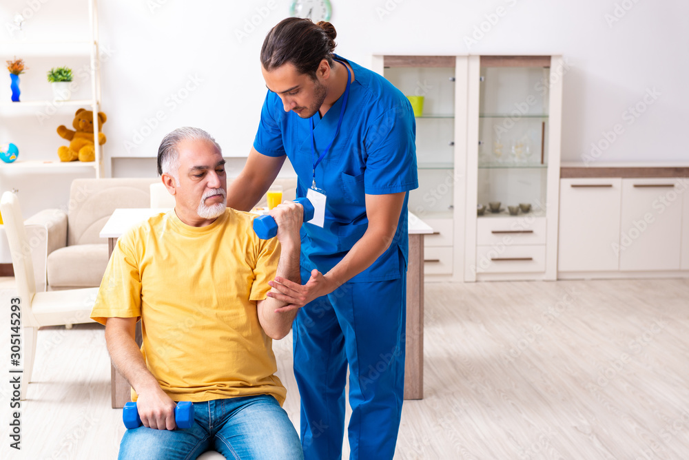 Obraz premium Young male doctor visiting old patient at home