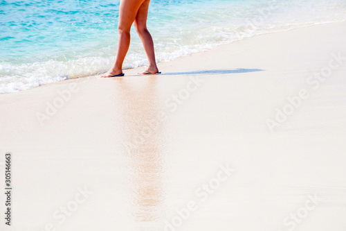 Woman standing on beach as a wave catches her feet on a beautiful tropical Grand Turk beach 