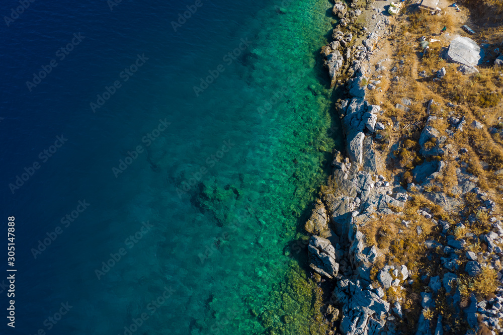 Aerial view to clear blue green sea with rocks, beautiful nature background. Greek island