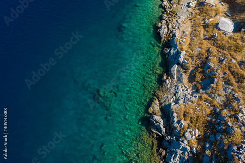 Aerial view to clear blue green sea with rocks, beautiful nature background. Greek island