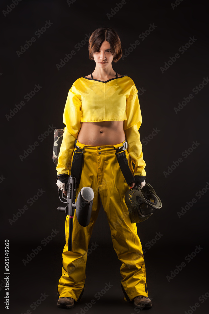 pretty woman in equipment with a paintball gun on a black background. Leisure pretty woman in equipment with a paintball gun on a black background. Leisure
