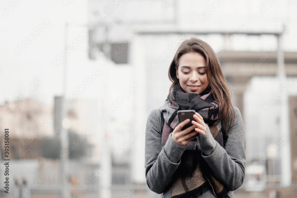 young attractive woman in the city holds a phone in her hands