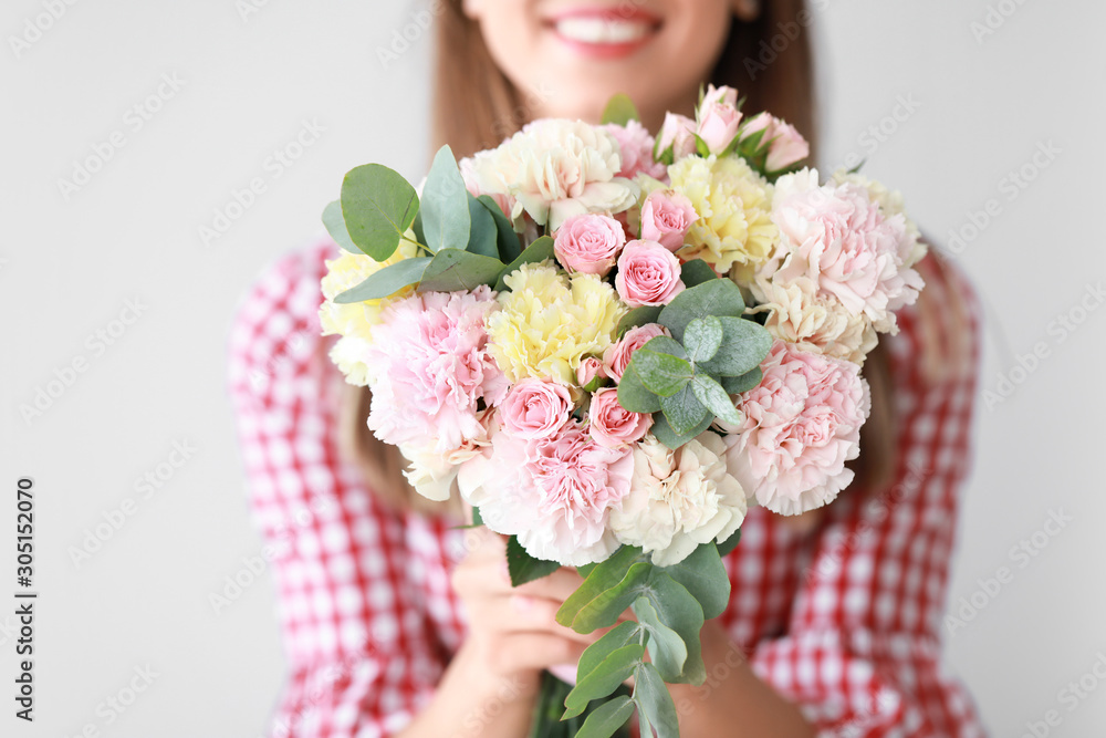 Beautiful young woman with bouquet of carnation flowers on light background, closeup