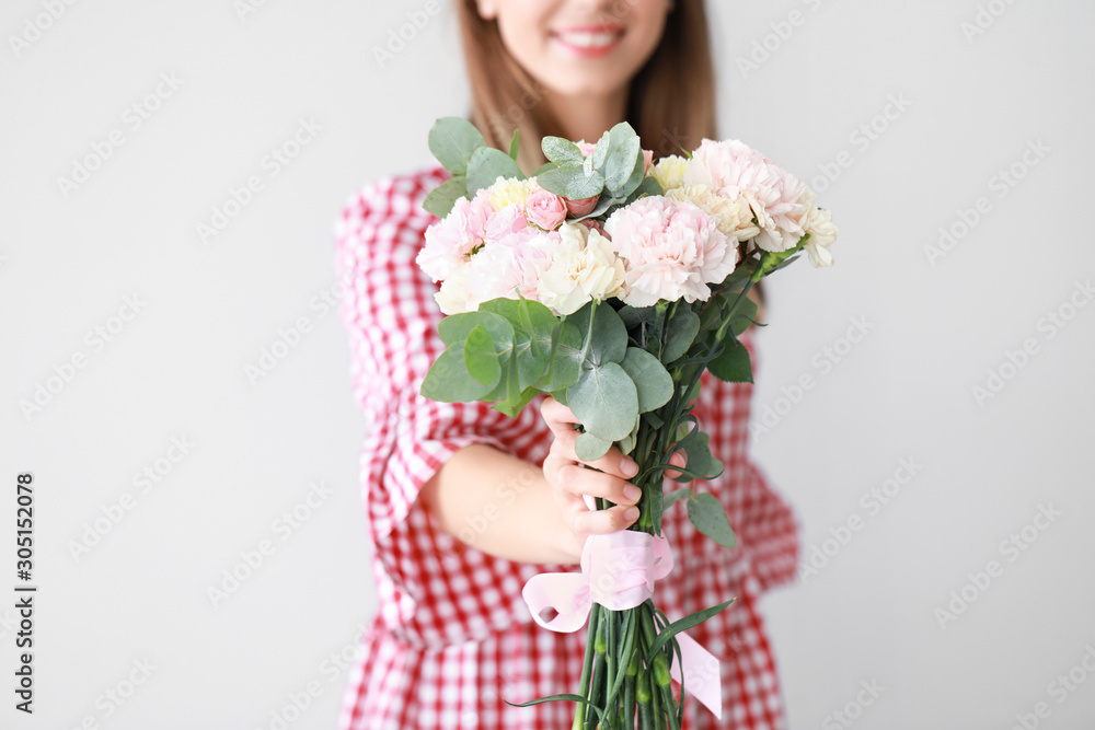 Beautiful young woman with bouquet of carnation flowers on light background Beautiful young woman with bouquet of carnation flowers on light background