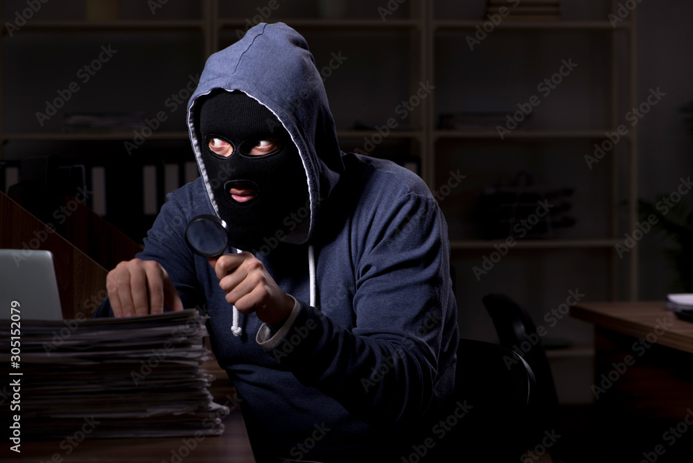 Male thief in balaclava in the office night time Male thief in balaclava in the office night time