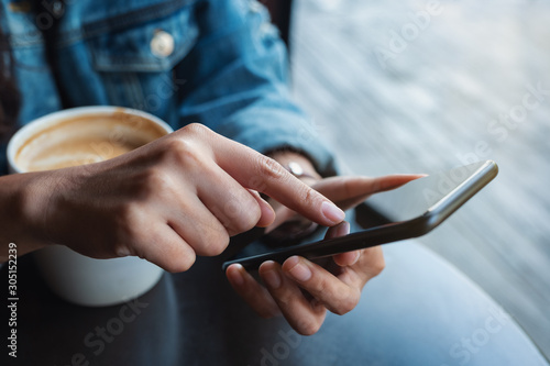 Closeup image of a woman holding and touching on mobile phone screen